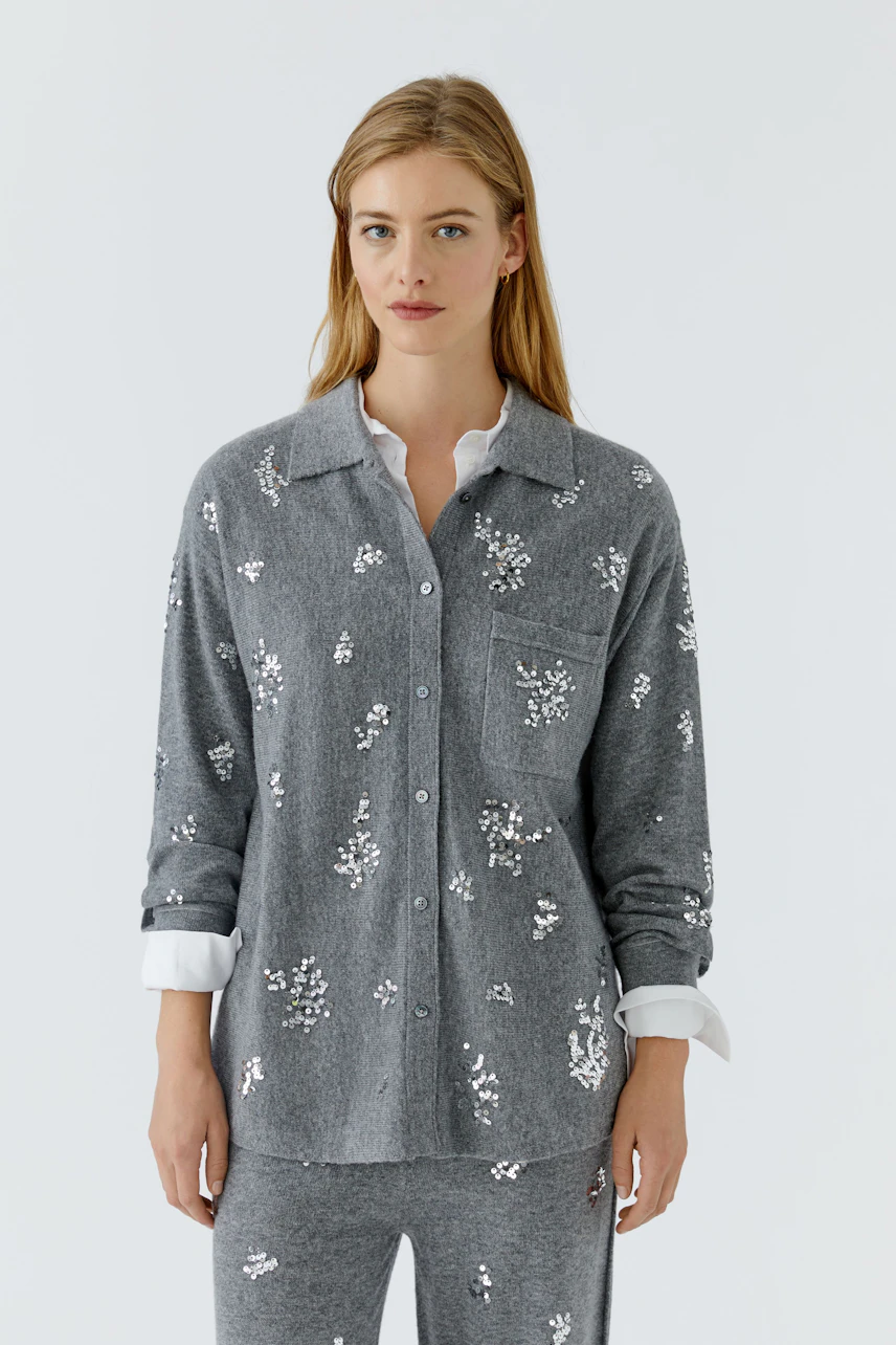 Graue Strickjacke: Frau trägt graue Strickjacke mit weißen Mustern, darunter weiße Bluse.