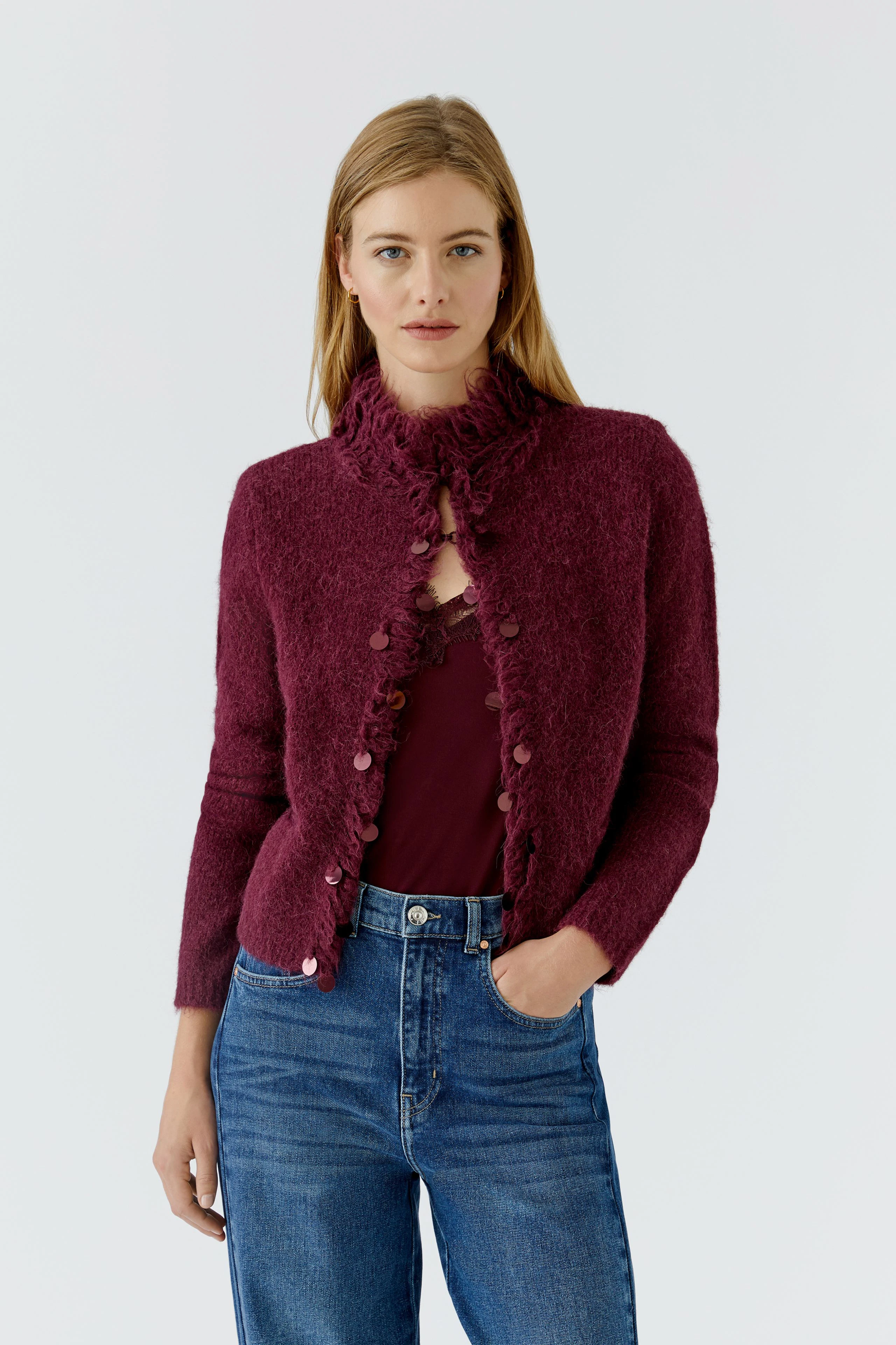 Woman in a cozy cardigan: Burgundy knit cardigan with button details, paired with casual jeans.