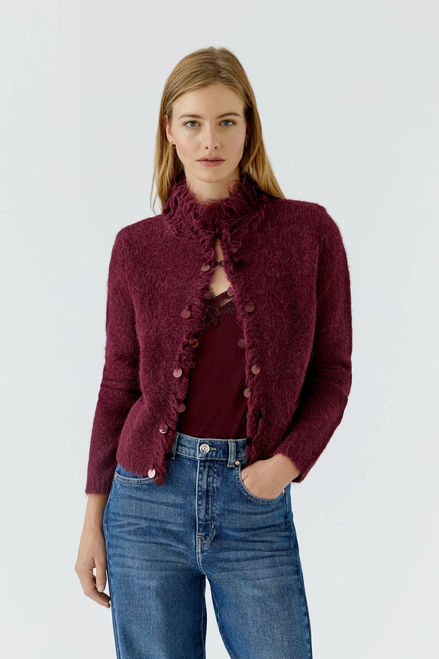 Woman in a cozy cardigan: Burgundy knit cardigan with button details, paired with casual jeans.