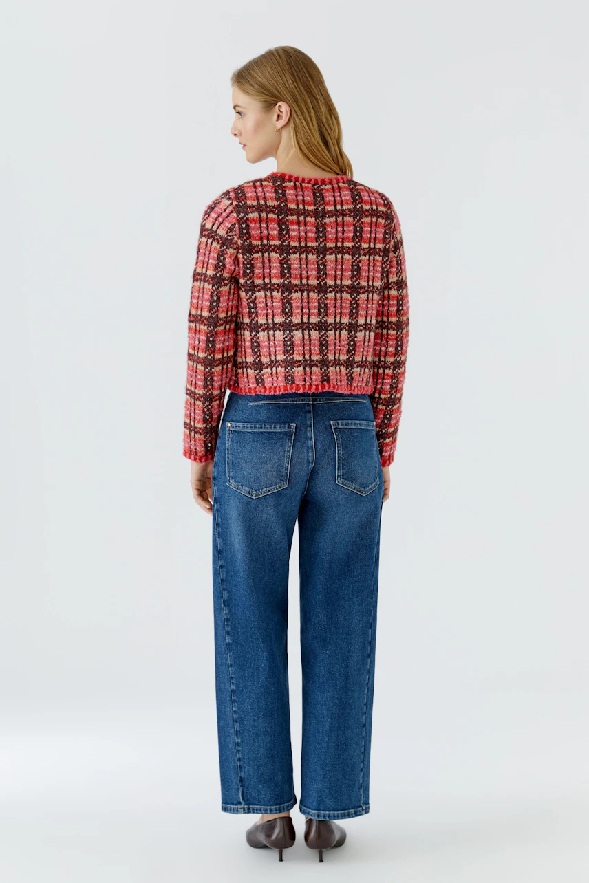Frau in karierter Strickjacke und blauer Jeans, Rückansicht. Lässiger Look für den Alltag.
