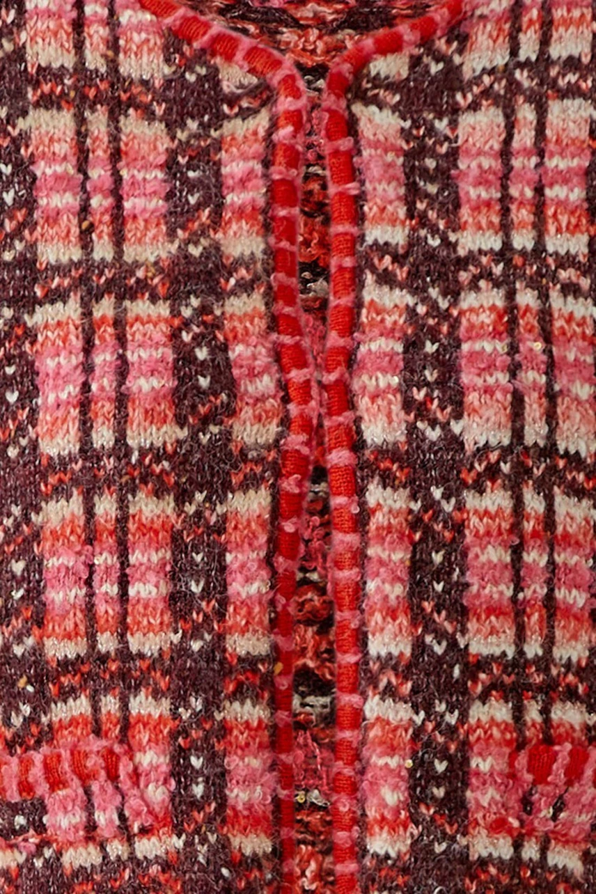 Frau in karierter Strickjacke: Lässiger Look mit roten und braunen Tönen, kombiniert mit blauer Jeans.