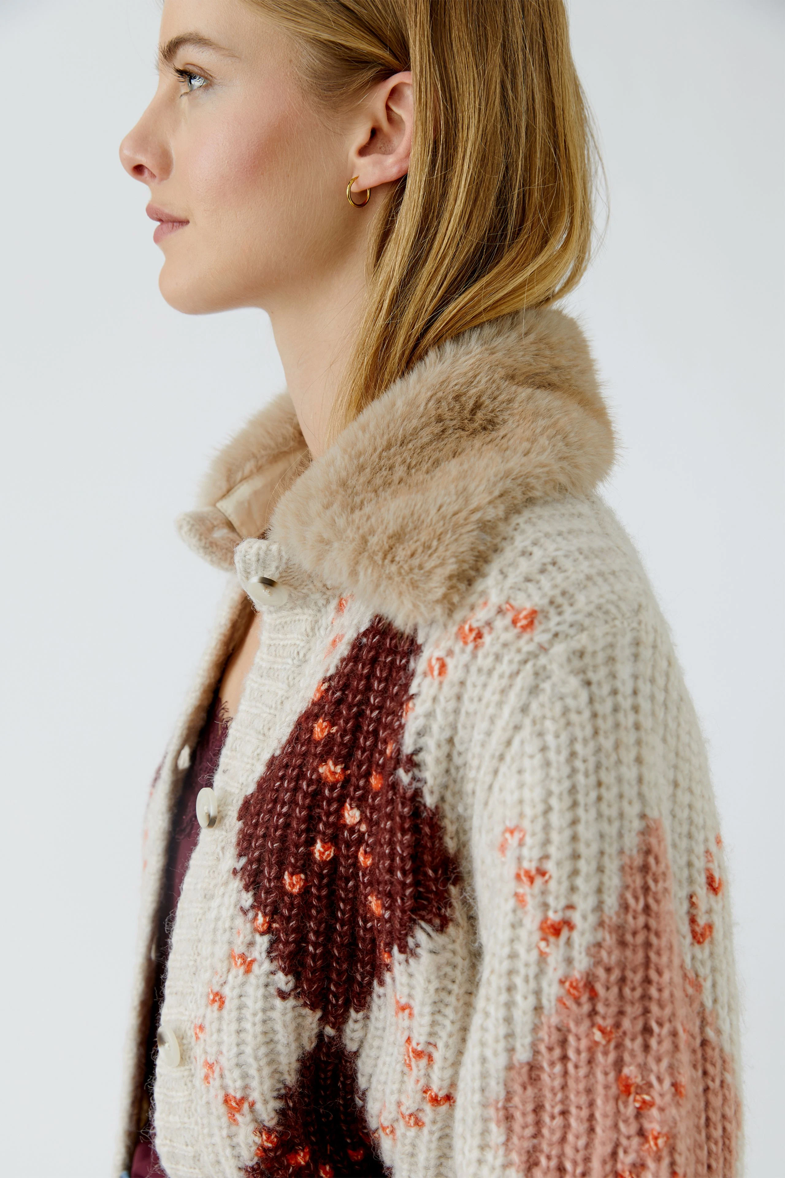 Strickjacke: Frau in gemusterter Strickjacke mit Kunstfellkragen, seitliches Profil.