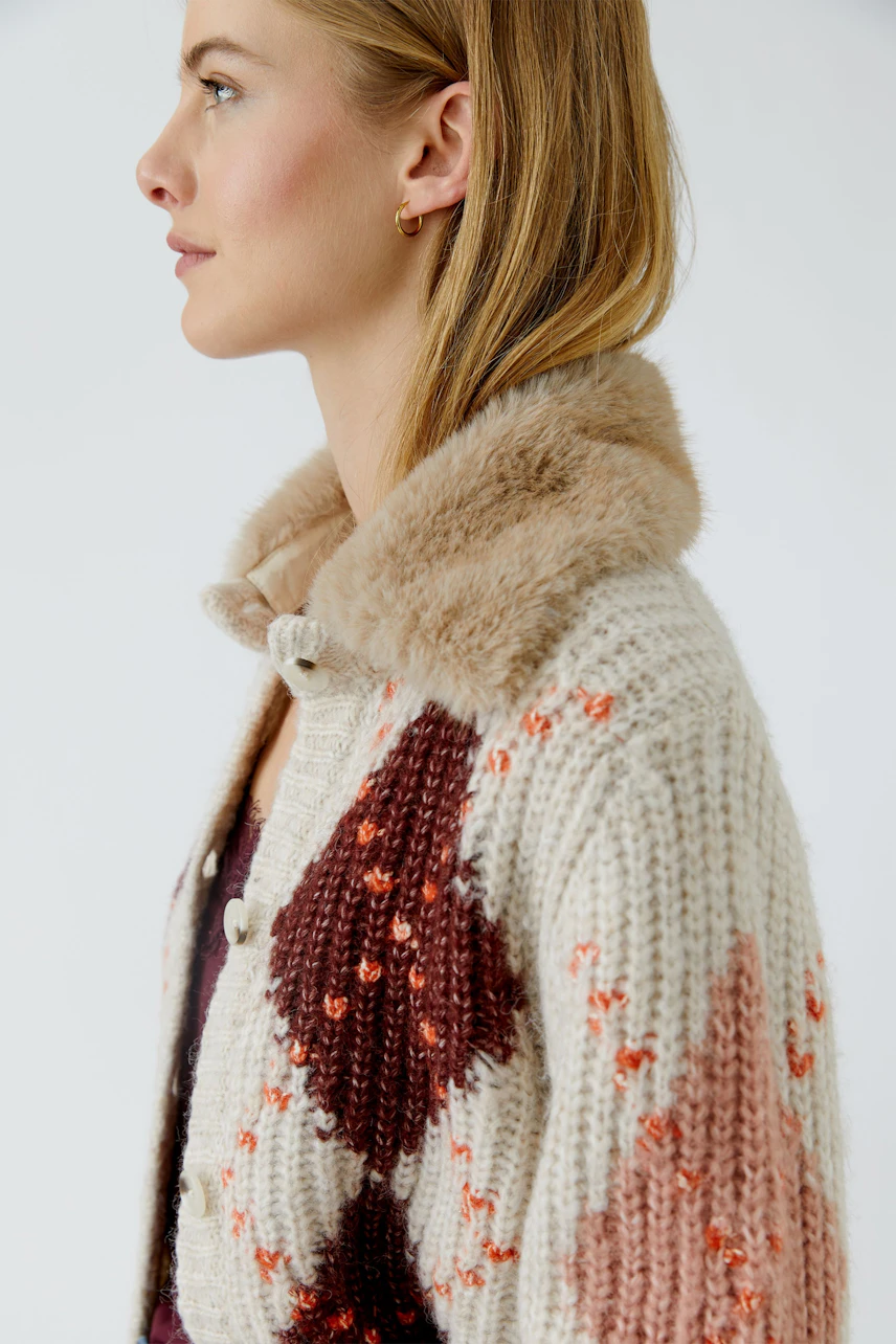 Strickjacke: Frau in gemusterter Strickjacke mit Kunstfellkragen, seitliches Profil.