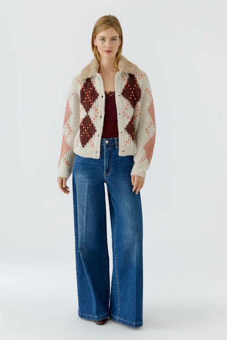 Strickjacke mit Karomuster und Kunstfellkragen, cremefarben mit roten Akzenten, ohne Model abgebildet.