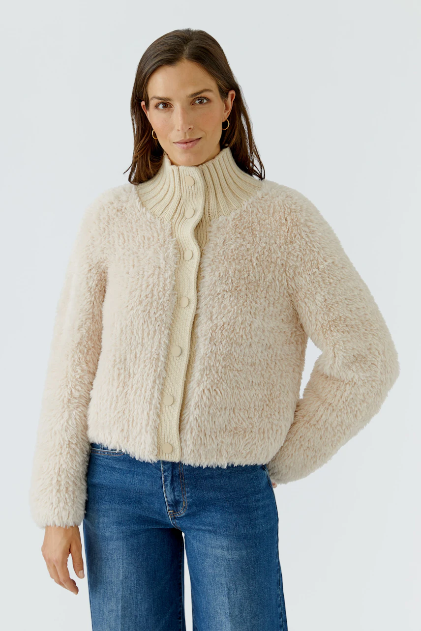Woman in cozy cardigan: Beige knit cardigan with buttons, worn by a woman in blue jeans, casual and warm.
