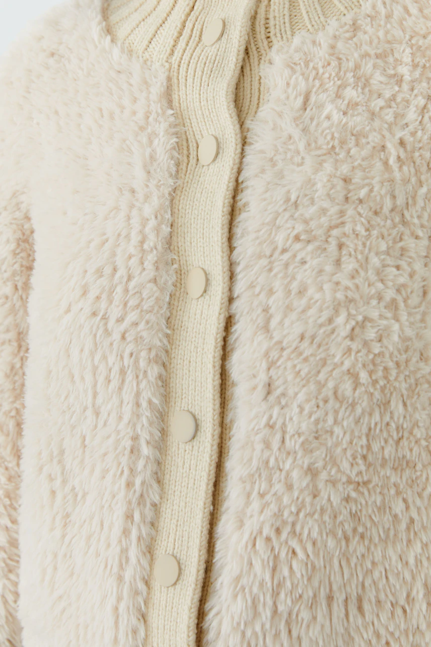Cozy cardigan: Beige knit cardigan with textured fabric and button closure, perfect for layering.