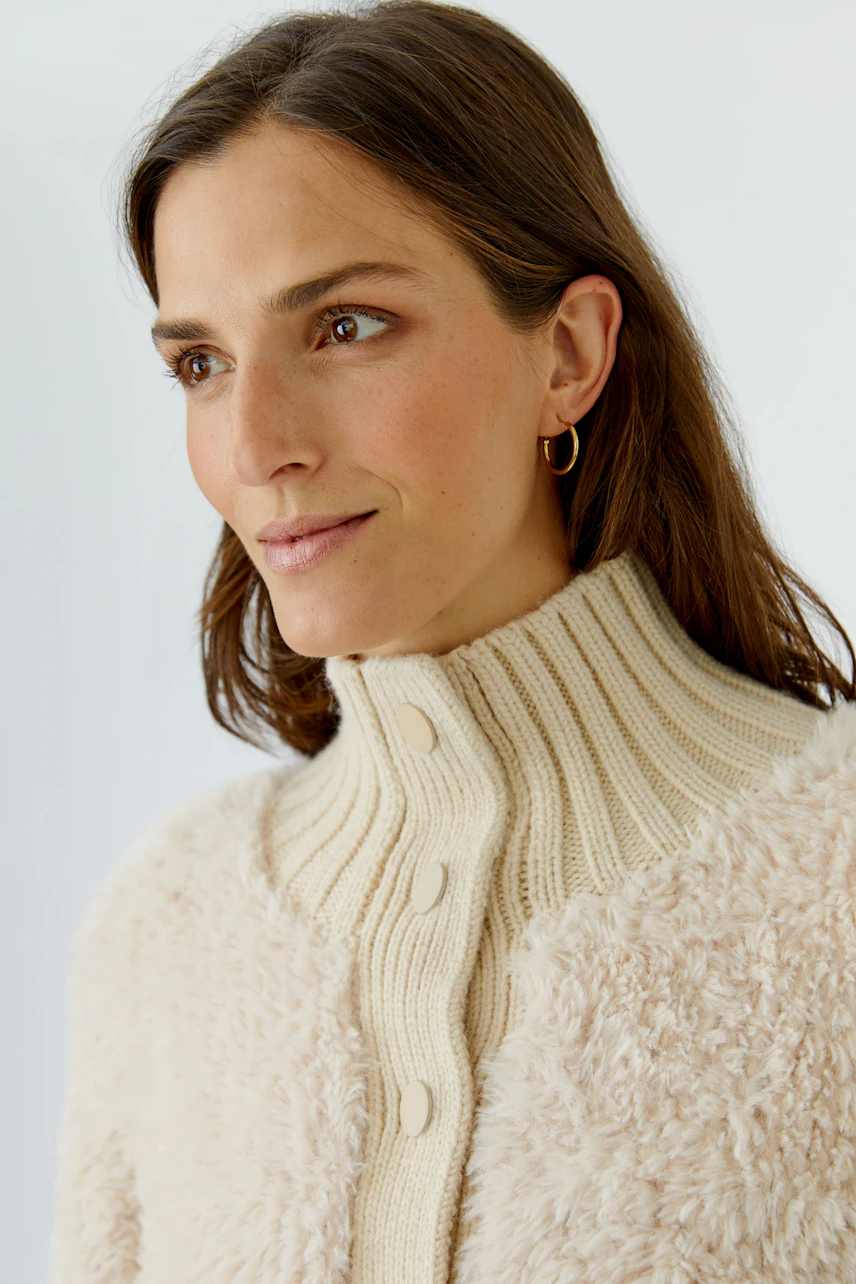Woman in cozy cardigan: Cream knit cardigan with textured fabric and button-up collar.