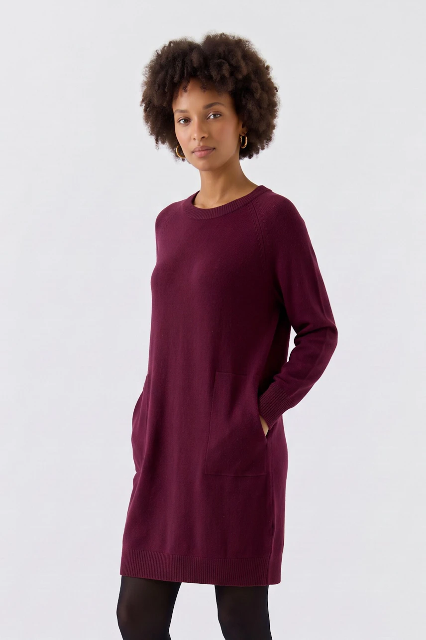 Casual knit dress: Woman in a burgundy knit dress with pockets, paired with brown leggings, looks relaxed.