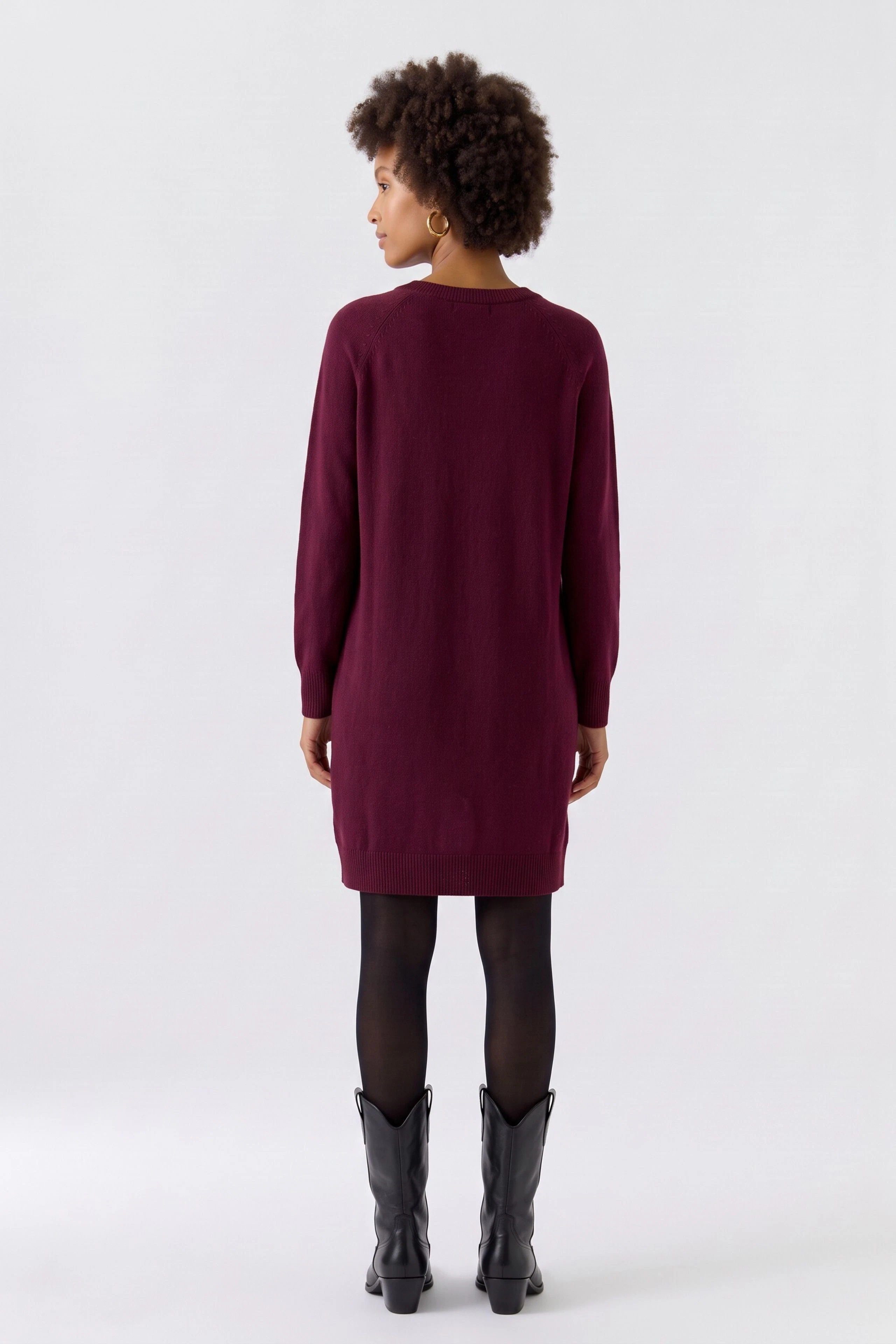 Strickkleid: Frau im weinroten Strickkleid, kombiniert mit brauner Lederhose, von hinten zu sehen.