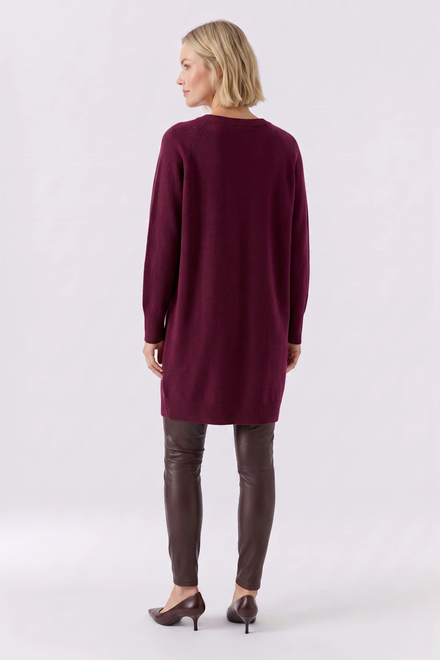 Strickkleid: Frau im weinroten Strickkleid, kombiniert mit brauner Lederhose, von hinten zu sehen.