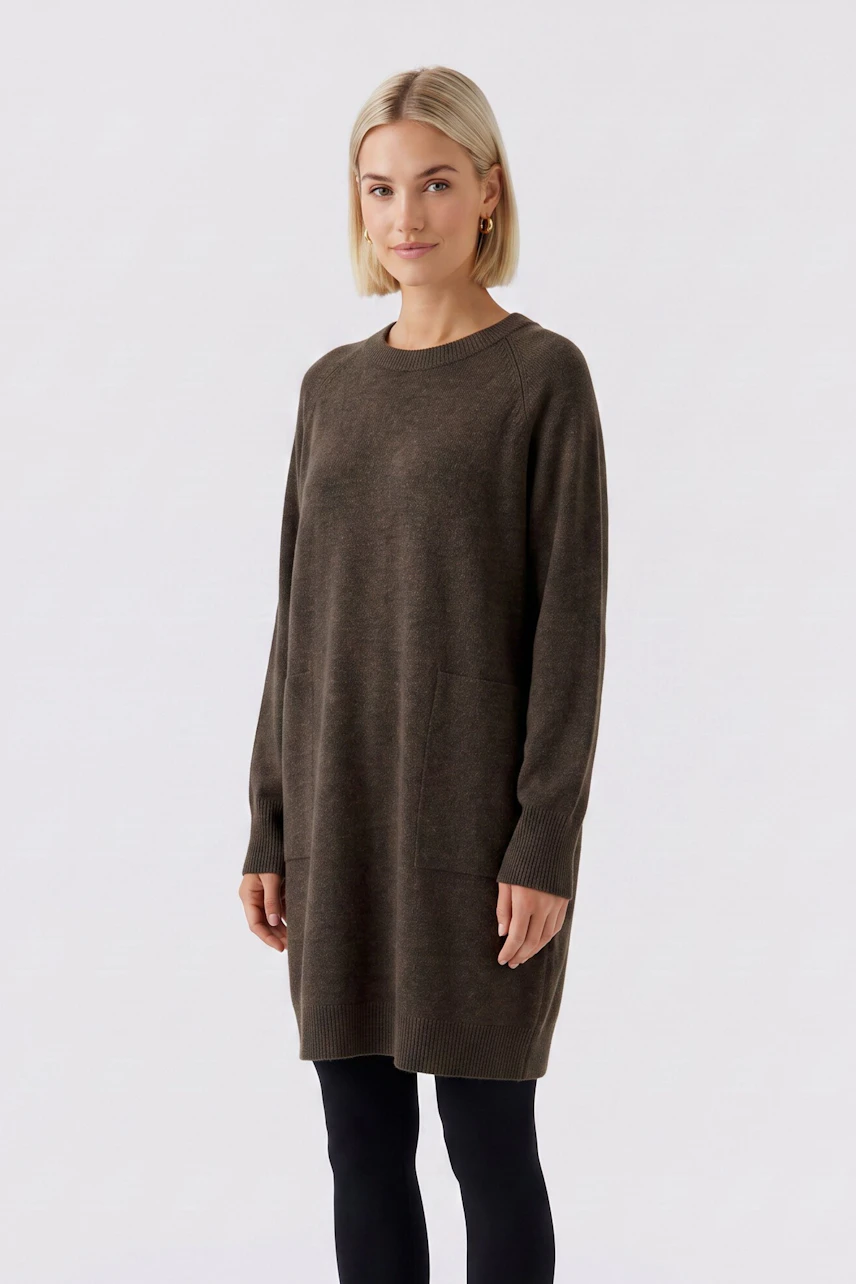 Strickkleid: Frau im braunen Strickkleid mit langen Ärmeln und legerem Schnitt, kombiniert mit schwarzen Leggings.