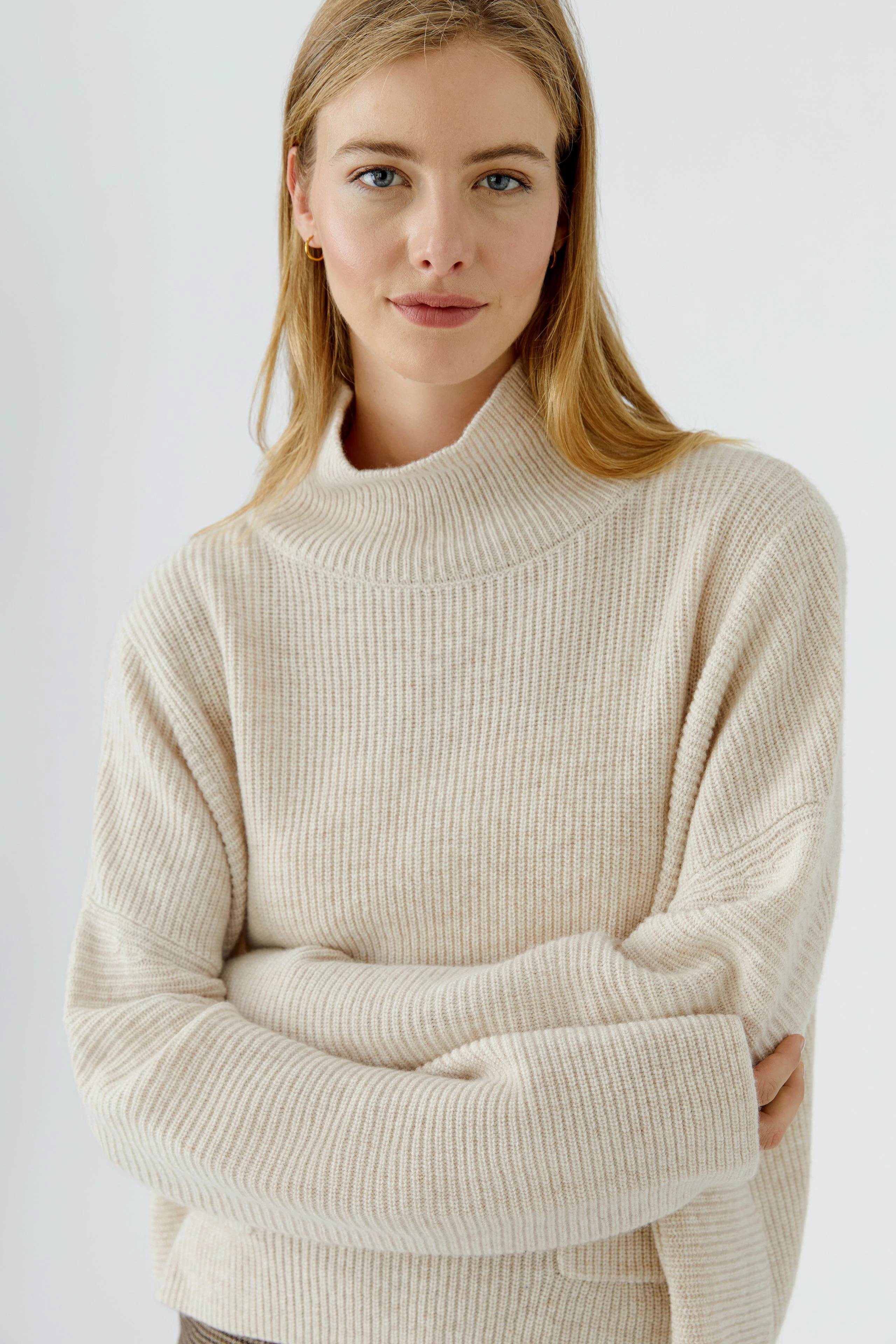 Frau im beigen Pullover: Lässiger Strickpullover mit hohem Kragen, ideal für kühle Tage.