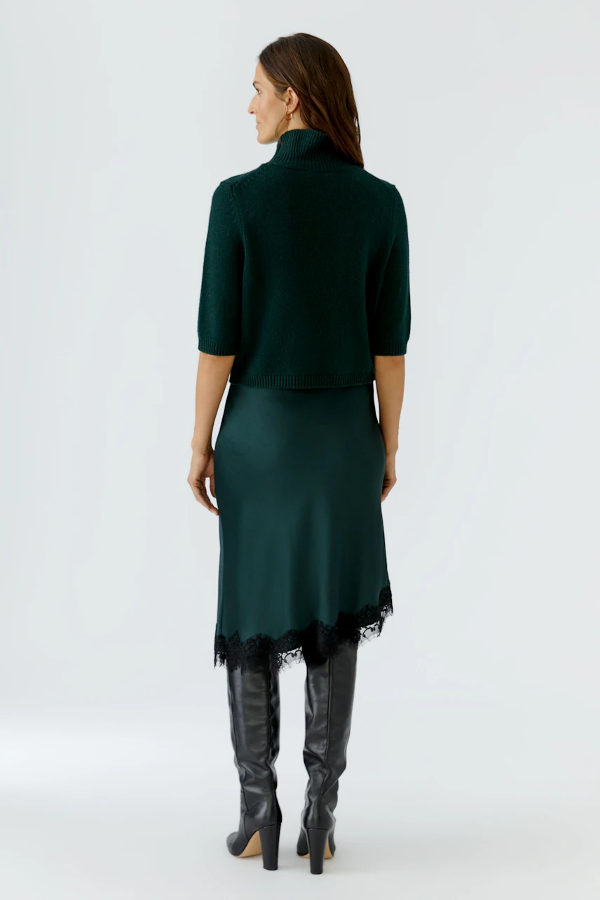 Casual women's pullover: Woman in a green pullover with half sleeves, paired with a sleek skirt and tall boots.
