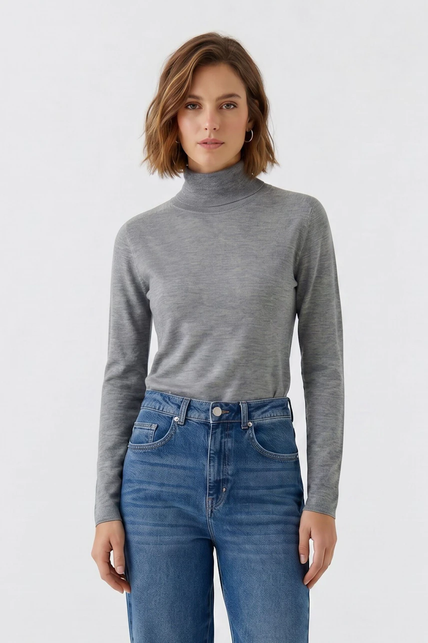 Casual women's pullover: Woman in a grey turtleneck pullover and blue jeans, standing confidently.