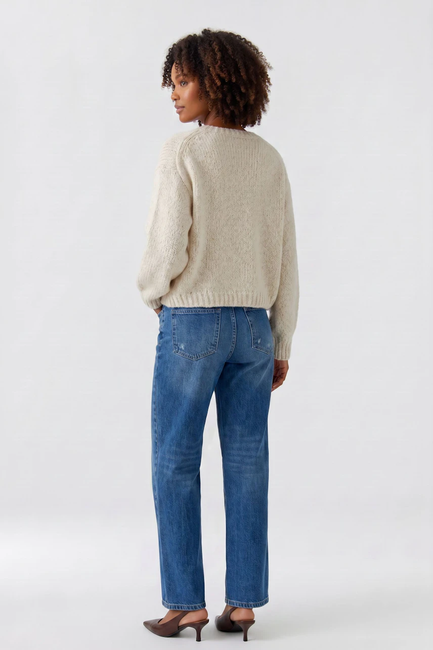 Lässiger Damen-Pullover: Frau im cremefarbenen Pullover und blauer Jeans, von hinten gesehen.
