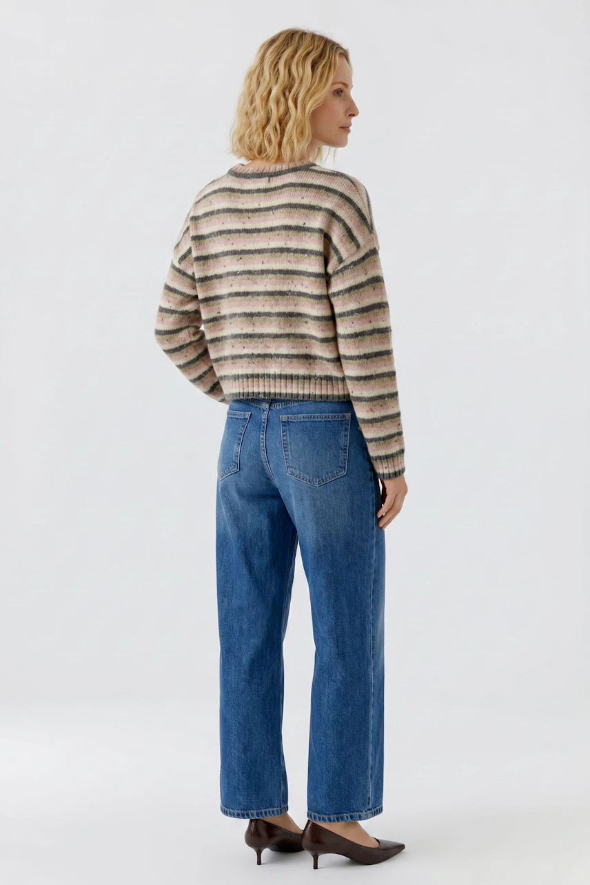 Gestreifter Damen-Pullover: Frau im lässigen Pullover und blauer Jeans, von hinten gesehen.