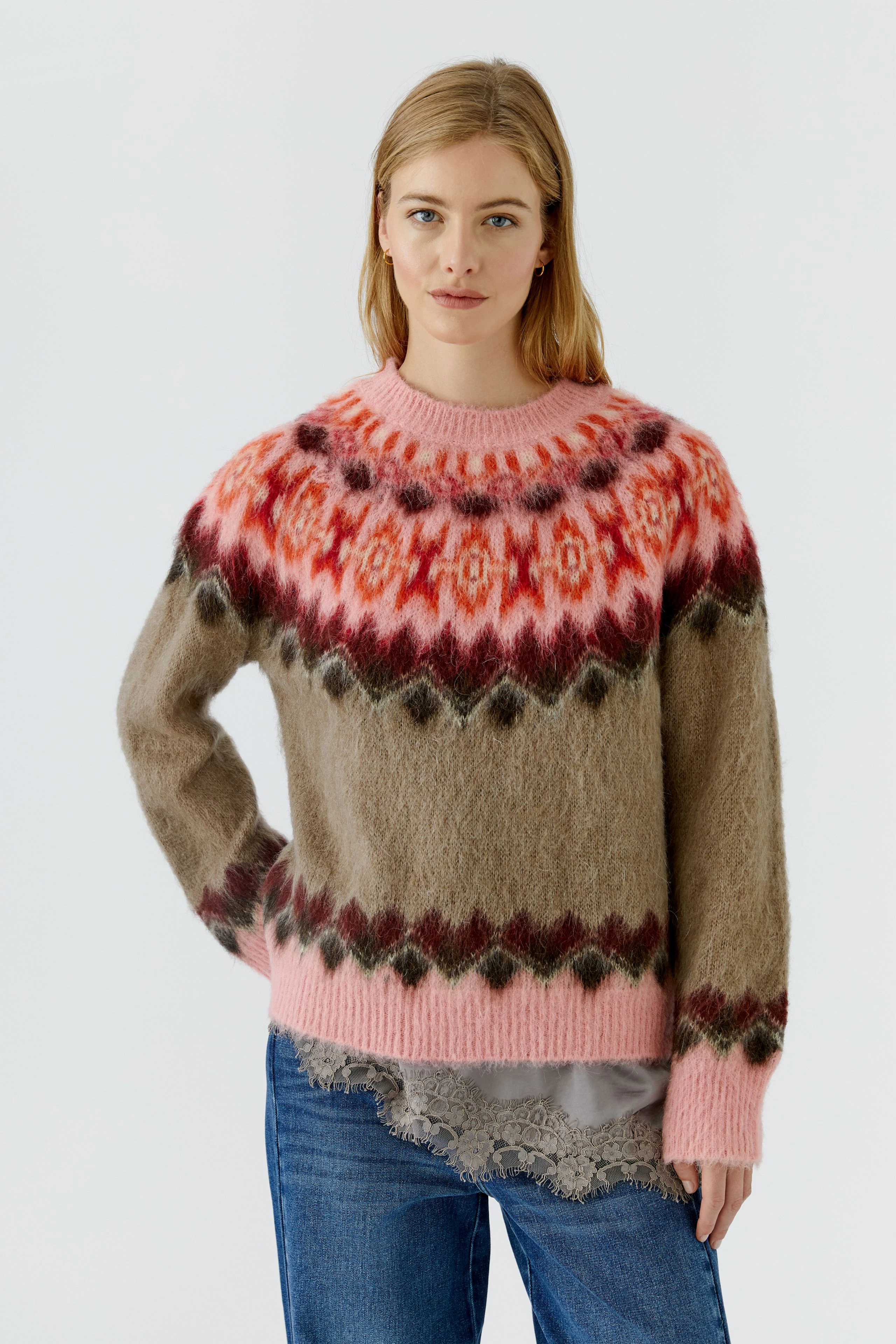 Frau im bunten Pullover mit Norwegermuster, kombiniert mit Jeans. Der Pullover ist flauschig und warm.