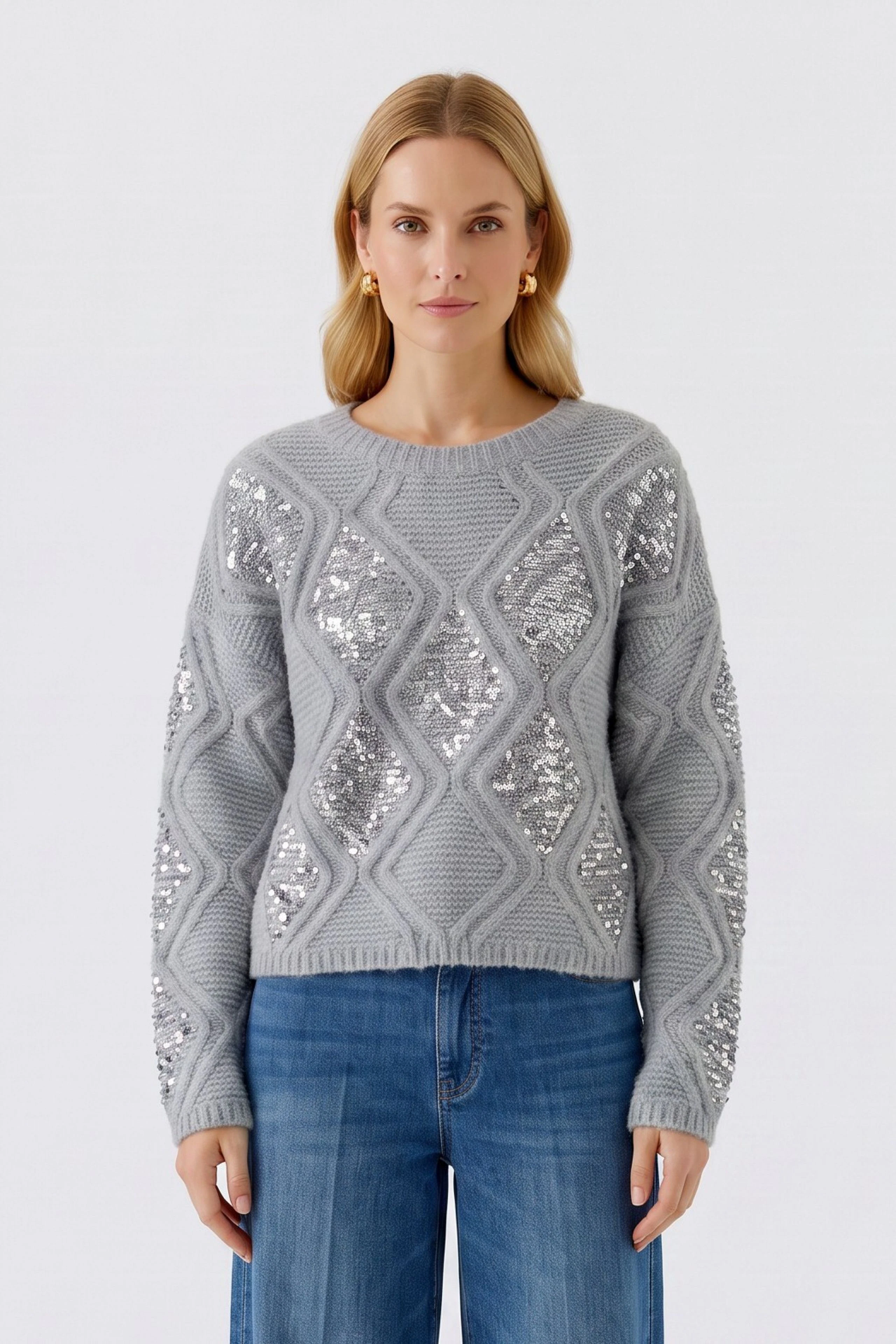 Grauer Damen-Pullover: Frau im Strickpullover mit glänzenden Details und blauer Jeans.