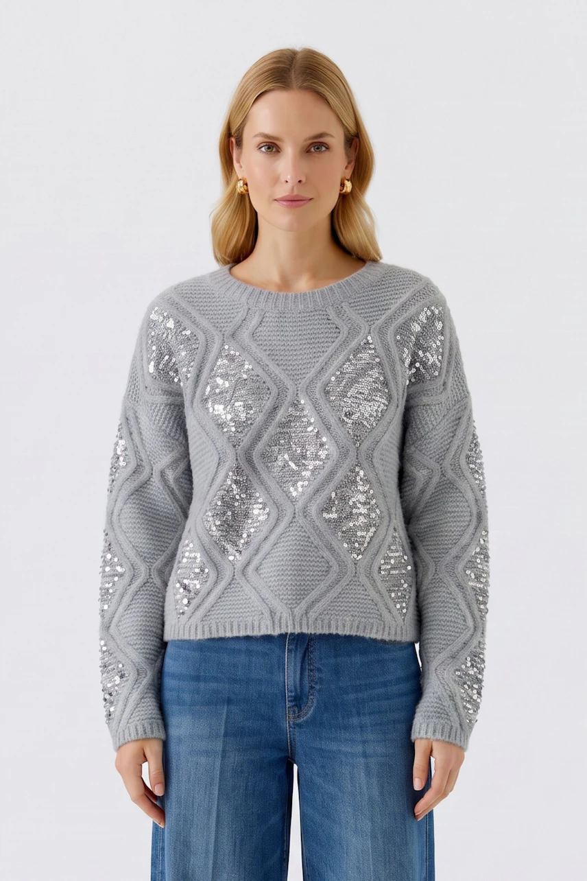 Grauer Damen-Pullover: Frau im Strickpullover mit glänzenden Details und blauer Jeans.