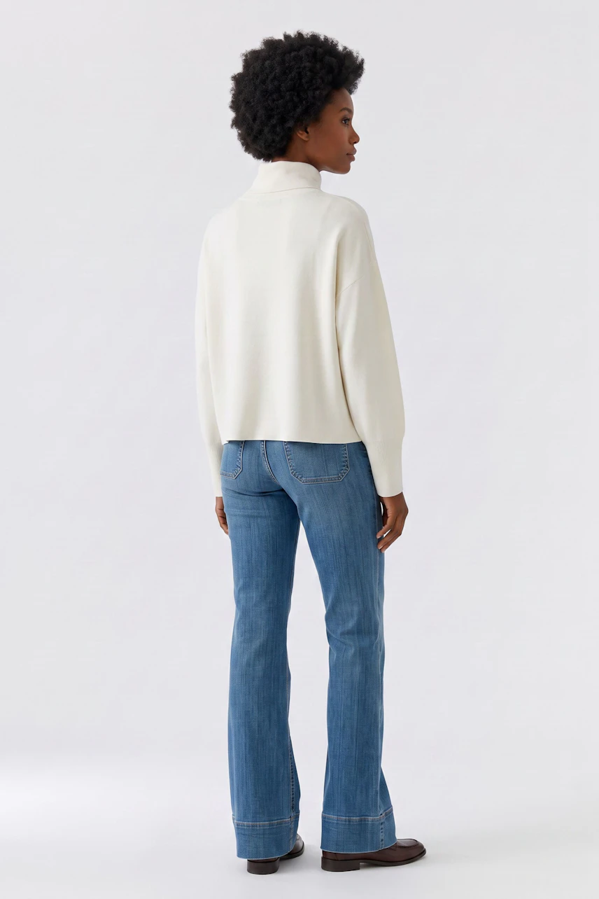 Damen-Pullover: Frau im weißen Pullover mit Rollkragen und blauer Jeans von hinten.