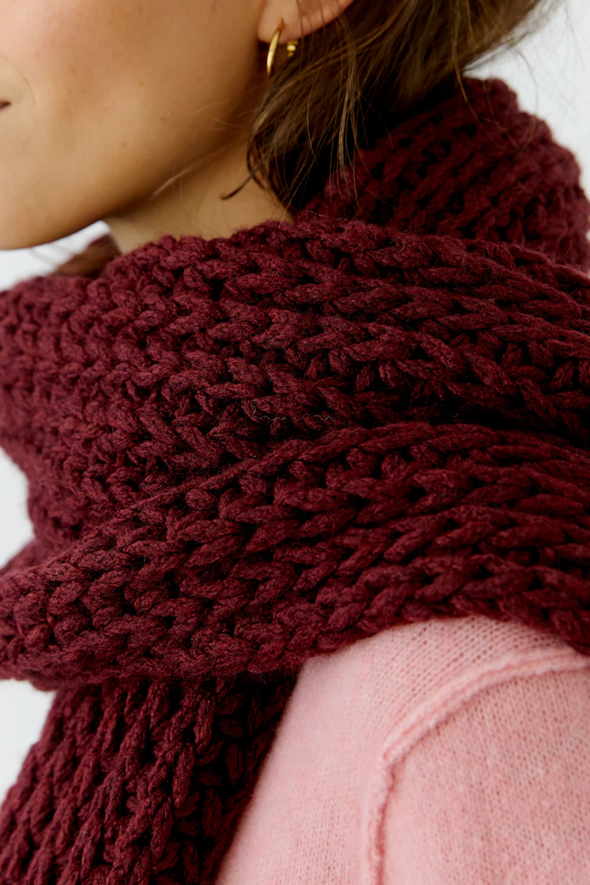 Dicker Strickschal: Frau trägt weinroten Schal über rosa Pullover, seitliches Profil sichtbar.