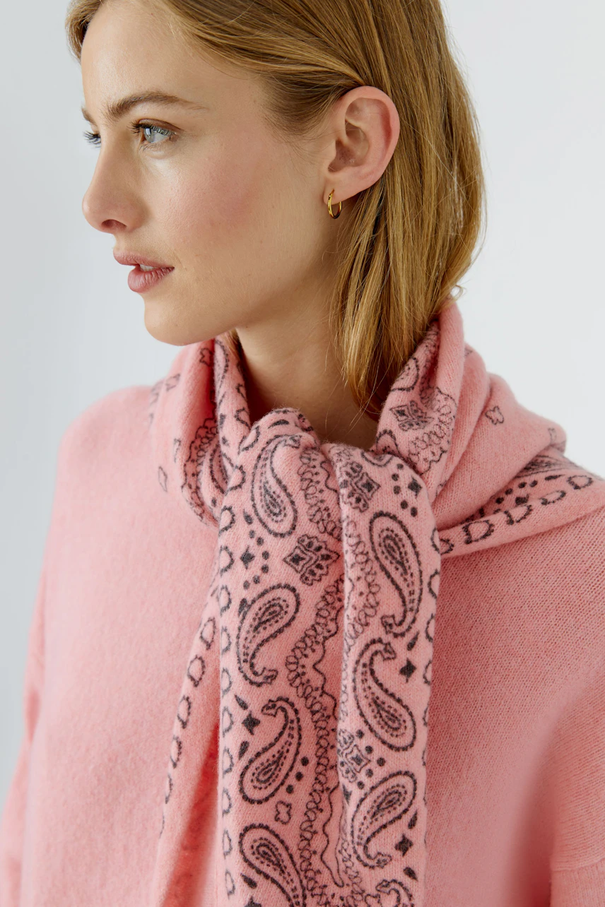 Frau mit rosa Schal: Junge Frau trägt einen gemusterten rosa Schal über einem passenden Pullover.