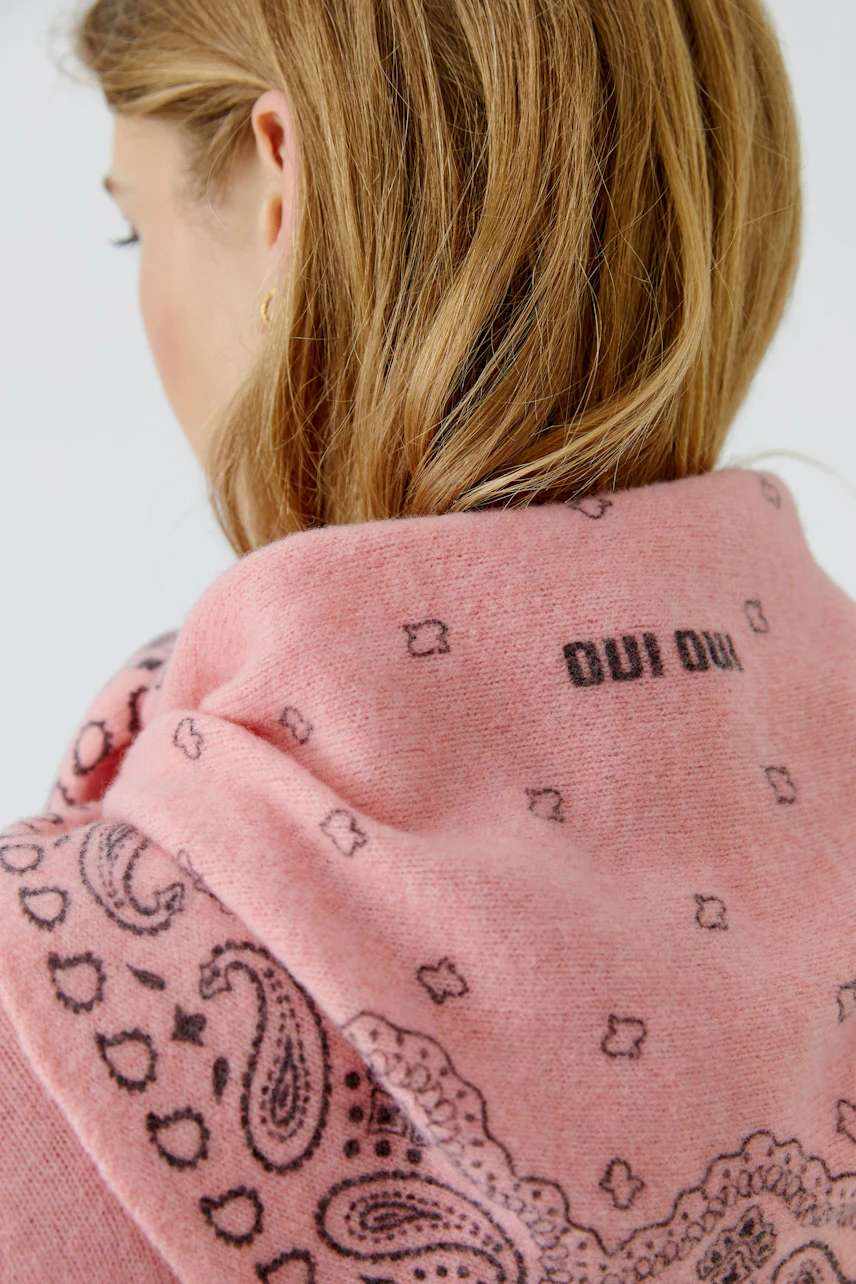 Rosa Schal mit Paisley-Muster: Frau trägt weichen Schal mit Oui-Logo, ideal für kühle Tage.
