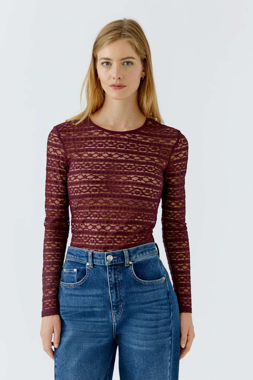 Frau im gemusterten Langarmshirt und Jeans. Schlichtes Design, ideal für lässige Outfits.