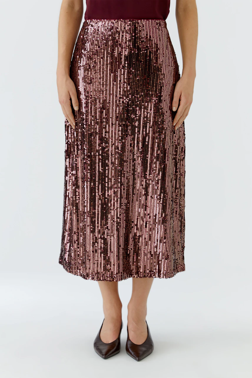 Woman in a shimmering pencil skirt, standing confidently. The skirt features a vibrant, textured design.