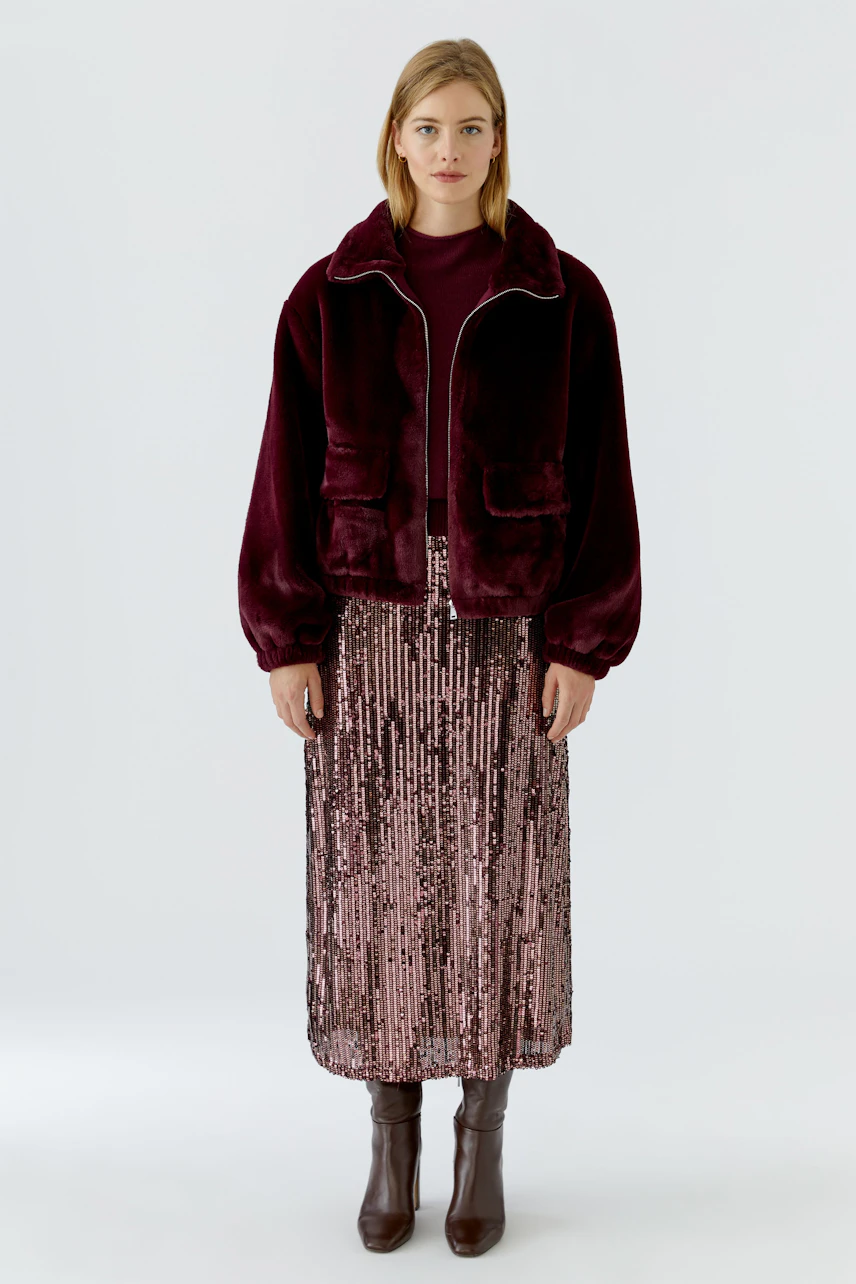 Damen-Blouson: Frau im weinroten Blouson mit passendem Rock und Stiefeln, stilvoll und modern.