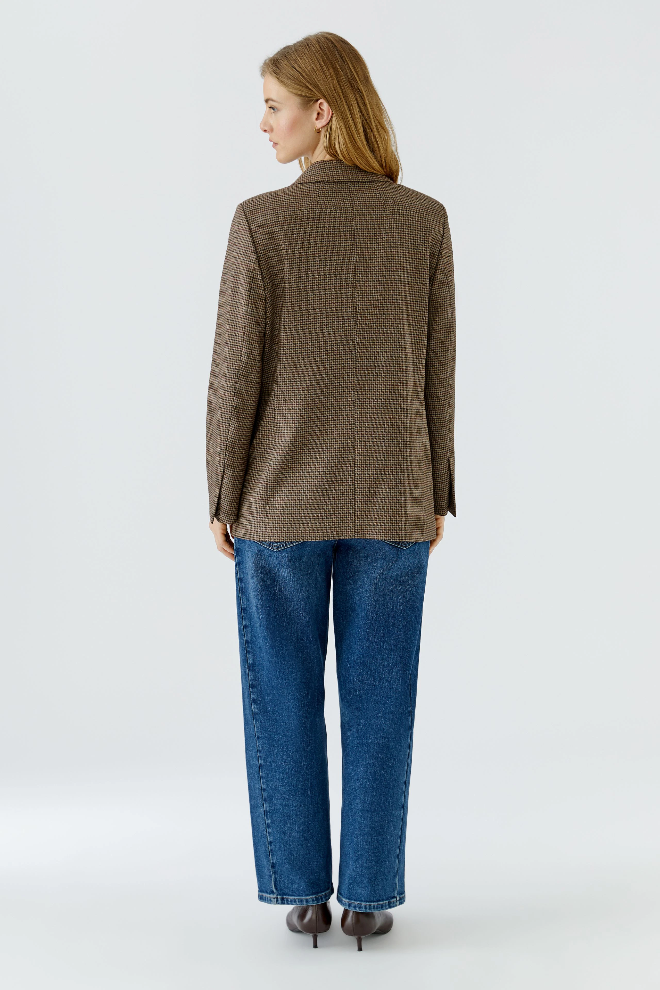Damen-Blazer: Frau im braunen Blazer und blauen Jeans, von hinten gesehen, steht aufrecht.