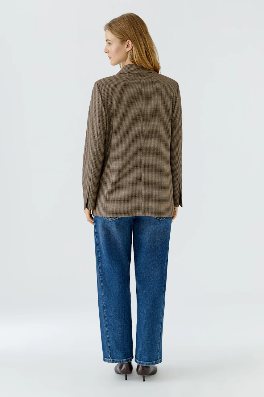 Casual women's blazer: Woman in a brown blazer and blue jeans, viewed from the back.
