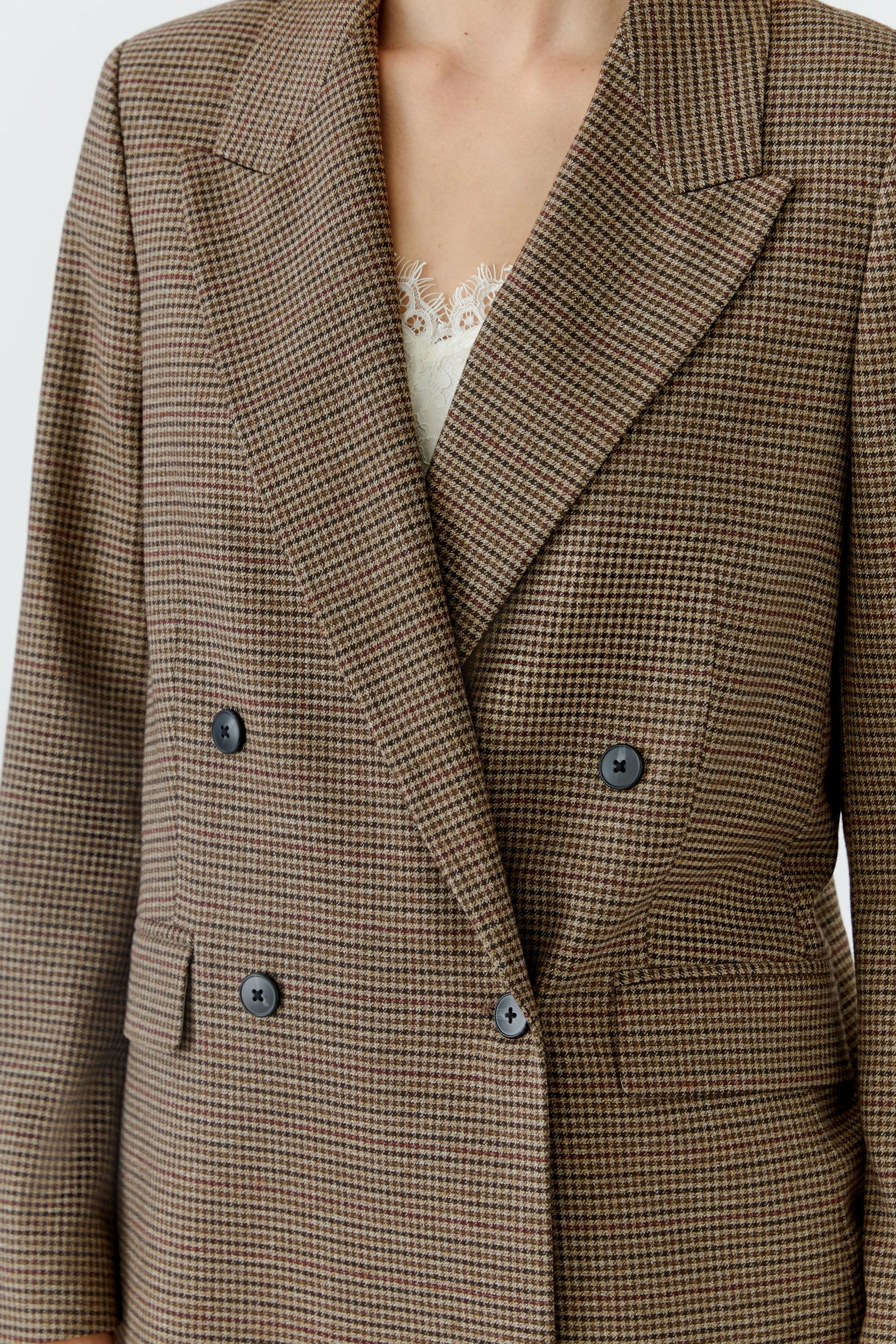 Klassischer Damen-Blazer: Frau im karierten Blazer mit dezentem Muster und Knopfleiste.