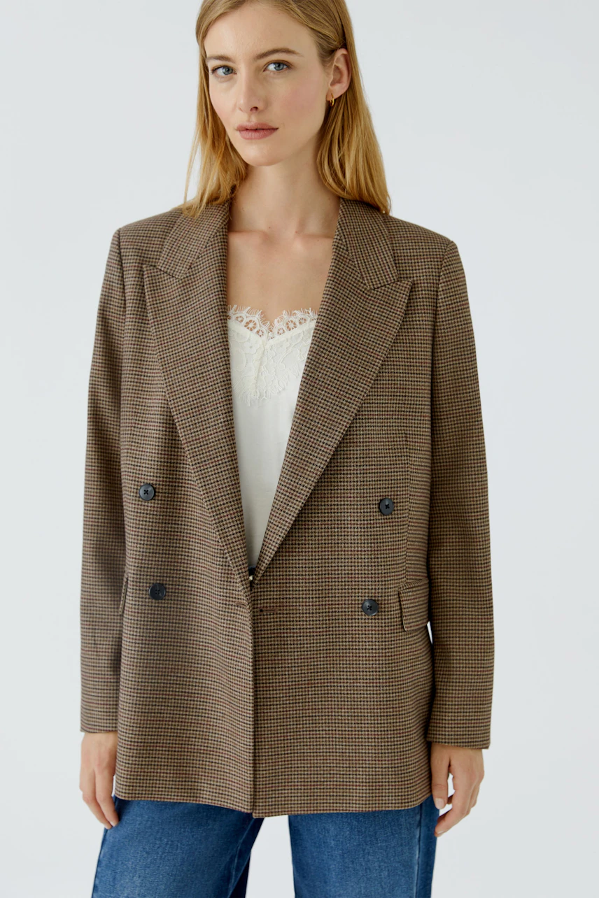 Casual blazer: Woman in a checked blazer over a white top and jeans, exuding a relaxed style.
