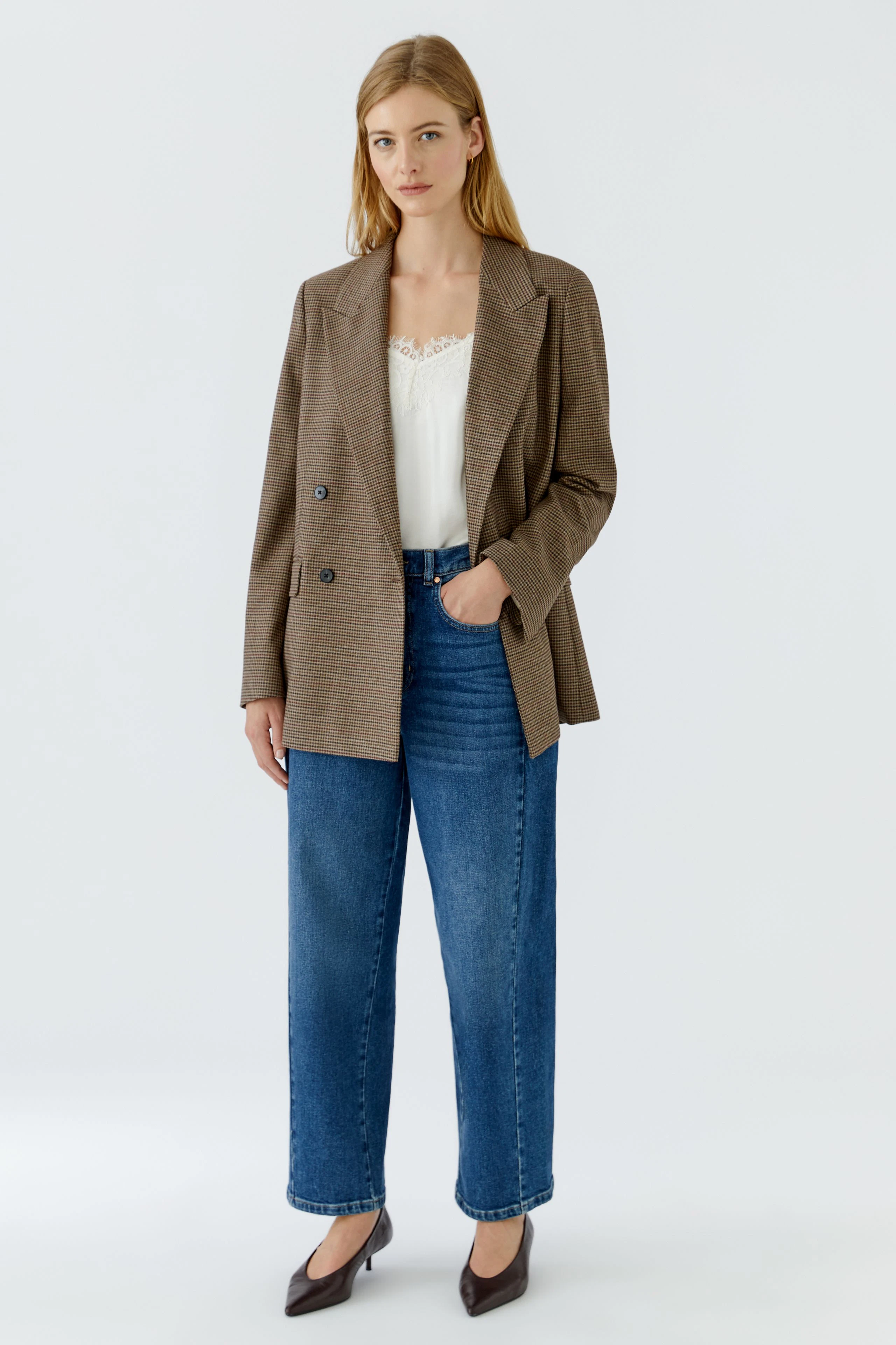 Damen-Blazer: Frau im karierten Blazer, weißem Top und blauer Jeans, steht selbstbewusst.