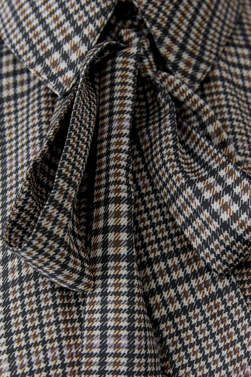 Checkered pussy-bow blouse: Close-up of the fabric with a classic bow detail.