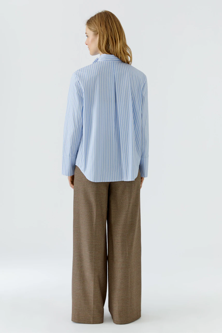 Woman in striped pussy-bow blouse and wide-leg trousers, viewed from the back.