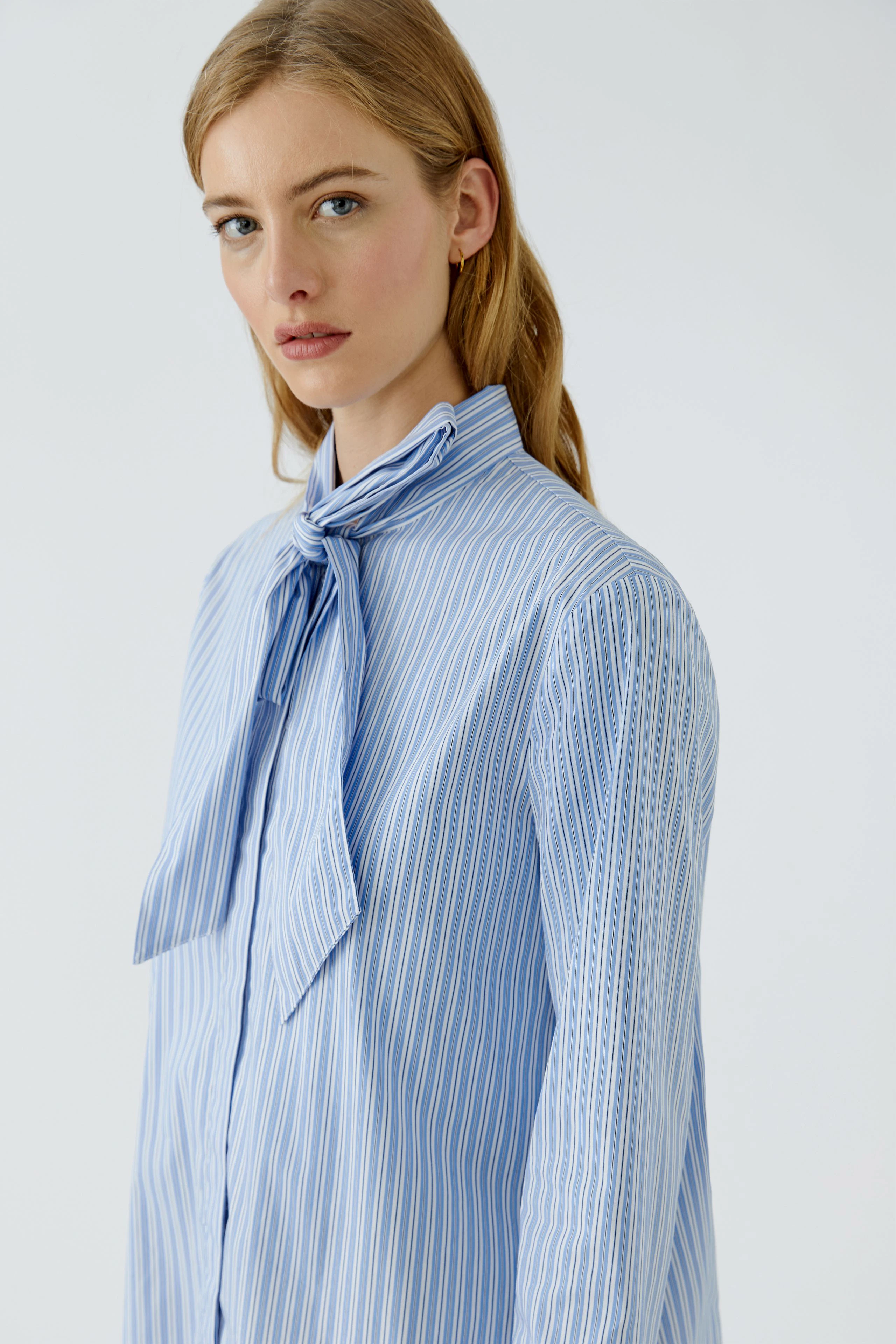 Frau in gestreifter Schluppenbluse: Blau-weißes Design, lässiger Look, selbstbewusster Ausdruck.