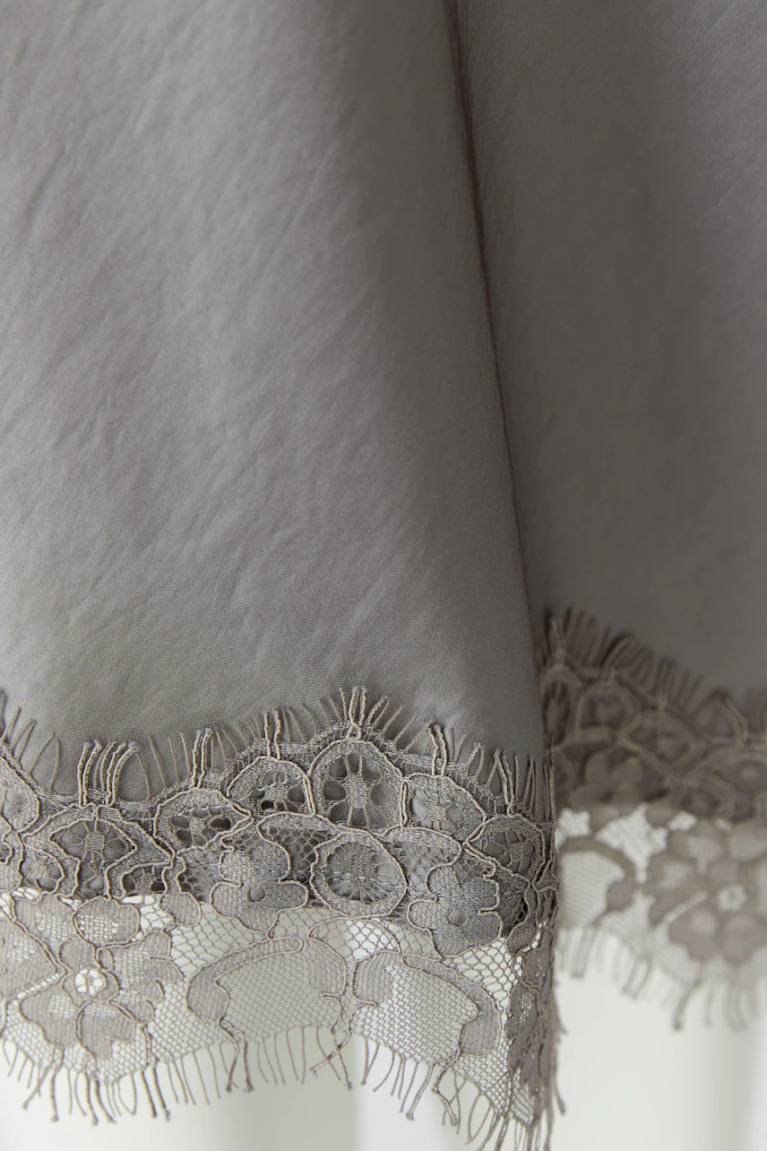 Grey pencil skirt with floral lace hem, showcasing intricate design and texture.