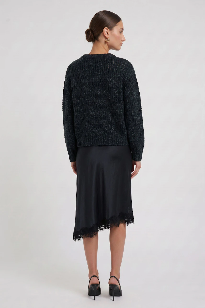 Woman in black pencil skirt with lace hem, paired with a textured pullover, viewed from the back.