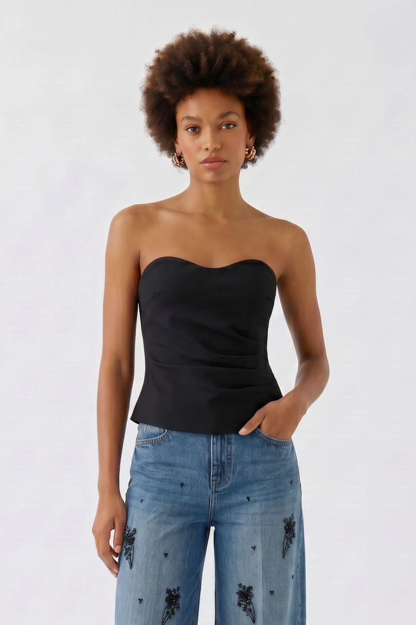 Schwarzes Damen-Top: Frau im schulterfreien Top kombiniert mit bestickter Jeans, lässig und modern.