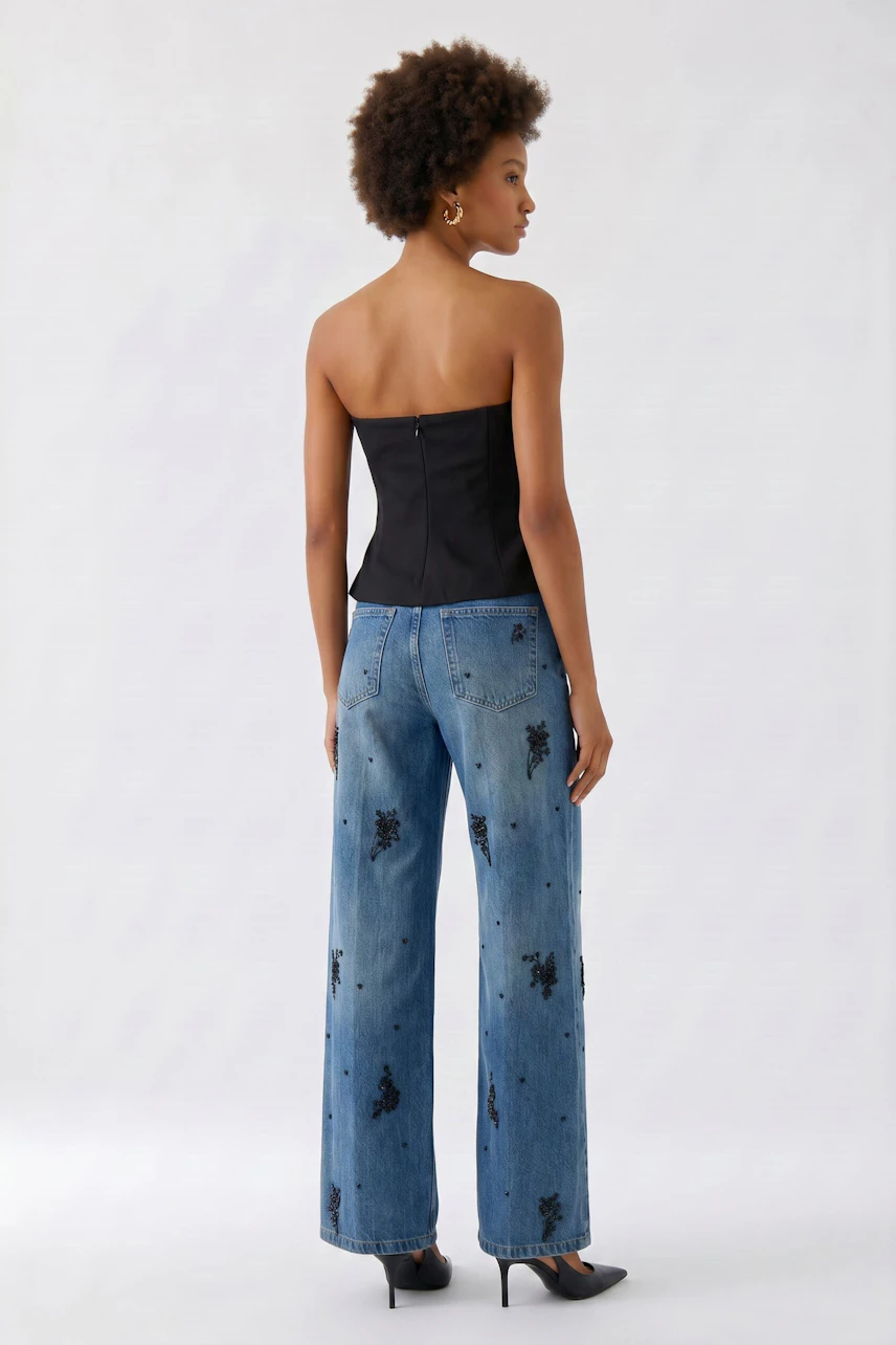 Schwarzes Damen-Top: Frau im schulterfreien Top mit blauer Jeans, Rückansicht, lässiger Look.