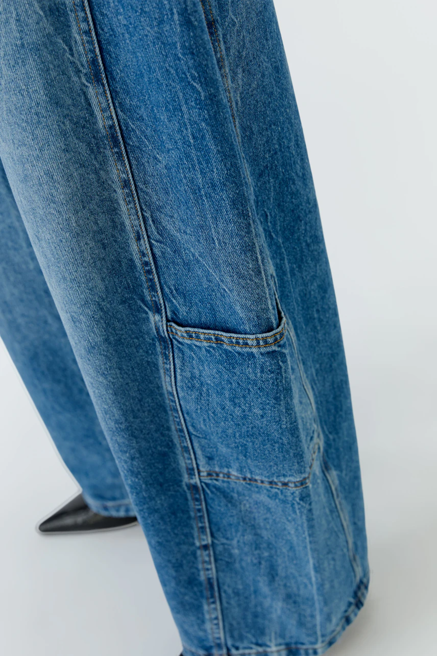 Jeans Barrel: Weite Jeans mit auffälligen Nähten und großen Taschen, präsentiert von einer Frau.