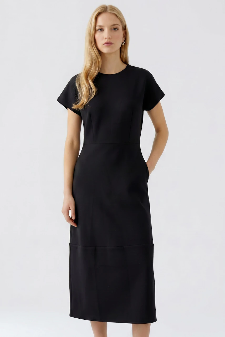 Casual dress: Woman in a black dress with short sleeves, standing confidently.