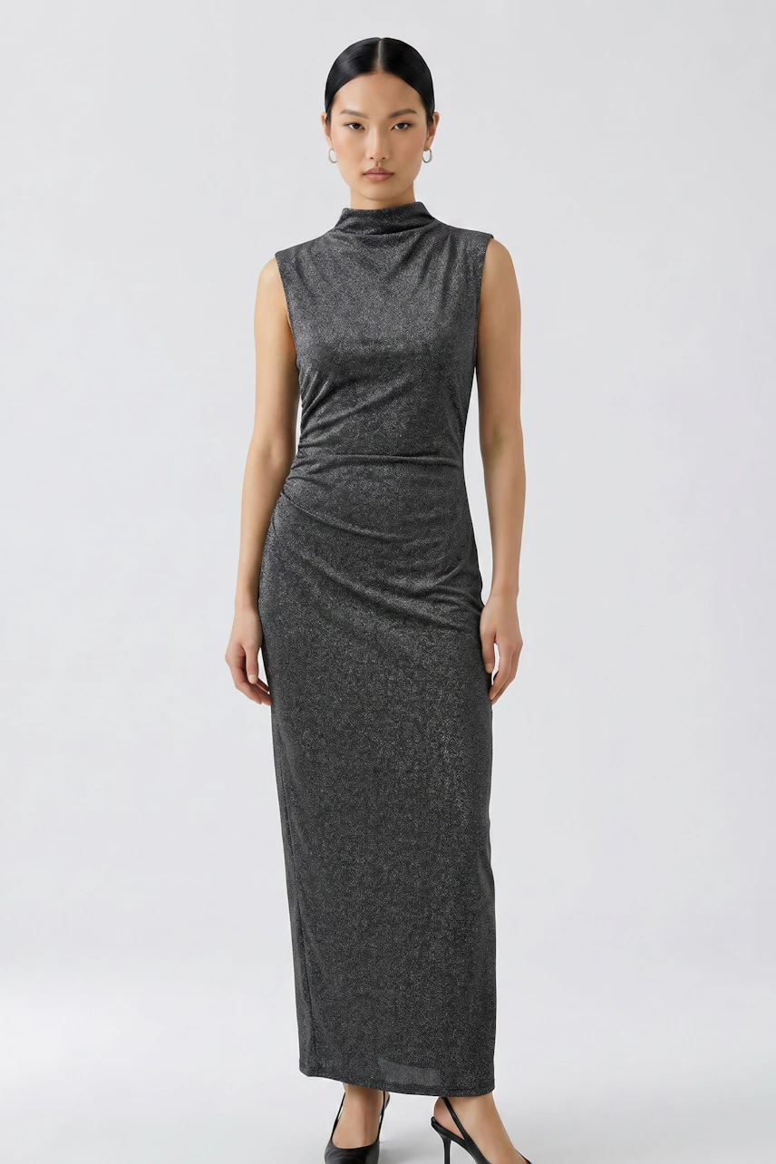 Woman in a sleek, sleeveless dress with a high neckline, standing confidently in black heels.