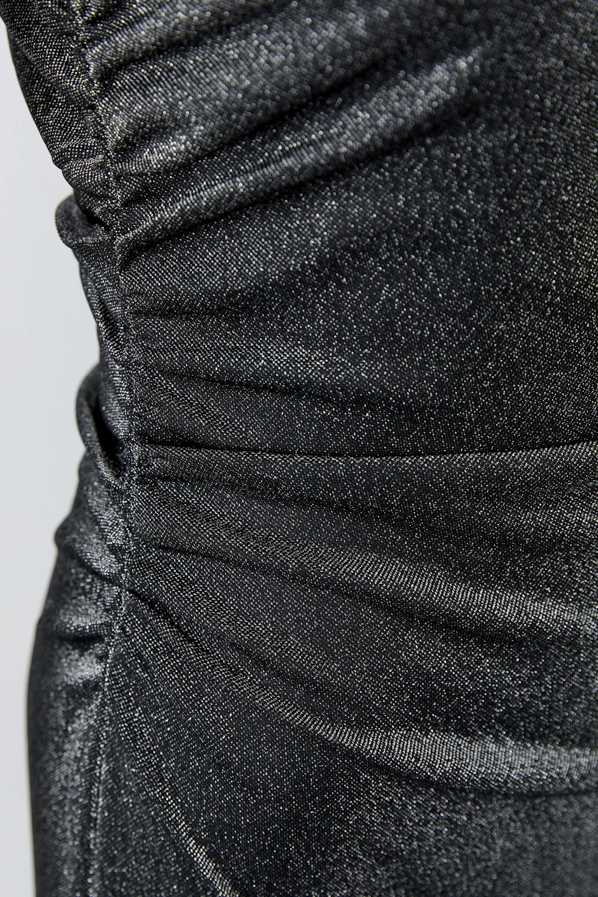 Black dress with ruched details, close-up of fabric texture, no model visible.