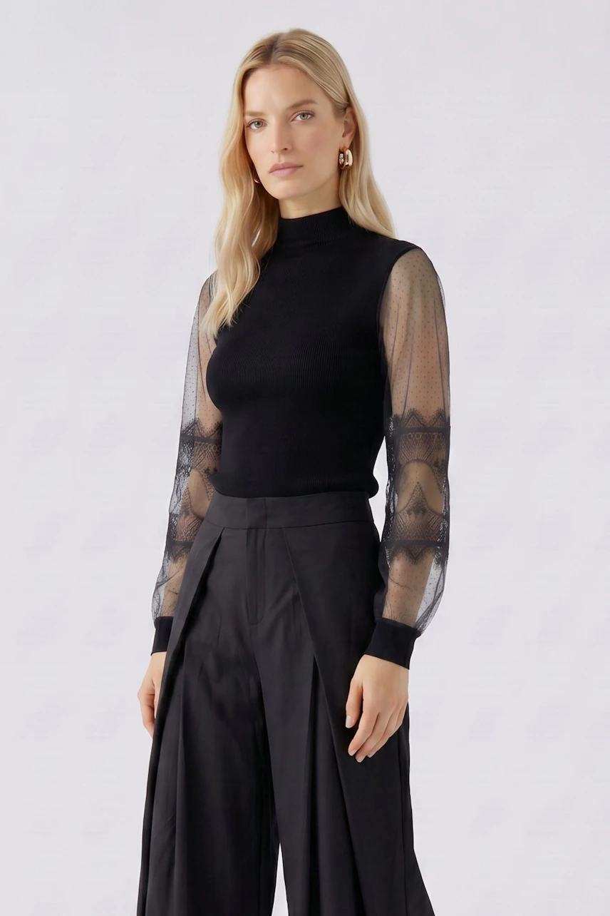 Damen-Pullover: Frau im schwarzen Pullover mit transparenten Ärmeln und weitem Hosenrock.