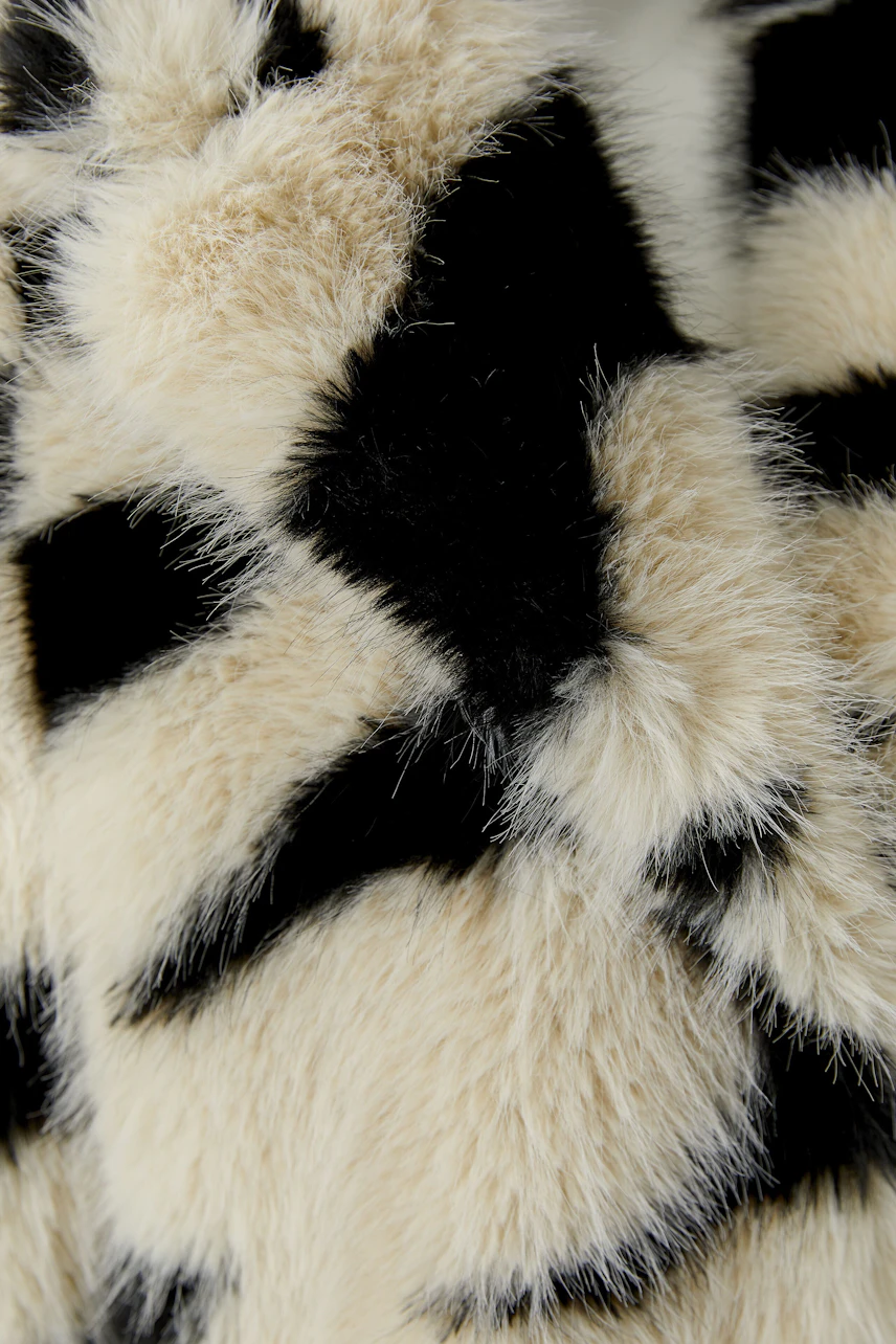 Stylischer Wintermantel: Flauschiger Mantel mit auffälligem Muster in Schwarz und Weiß für kalte Tage.