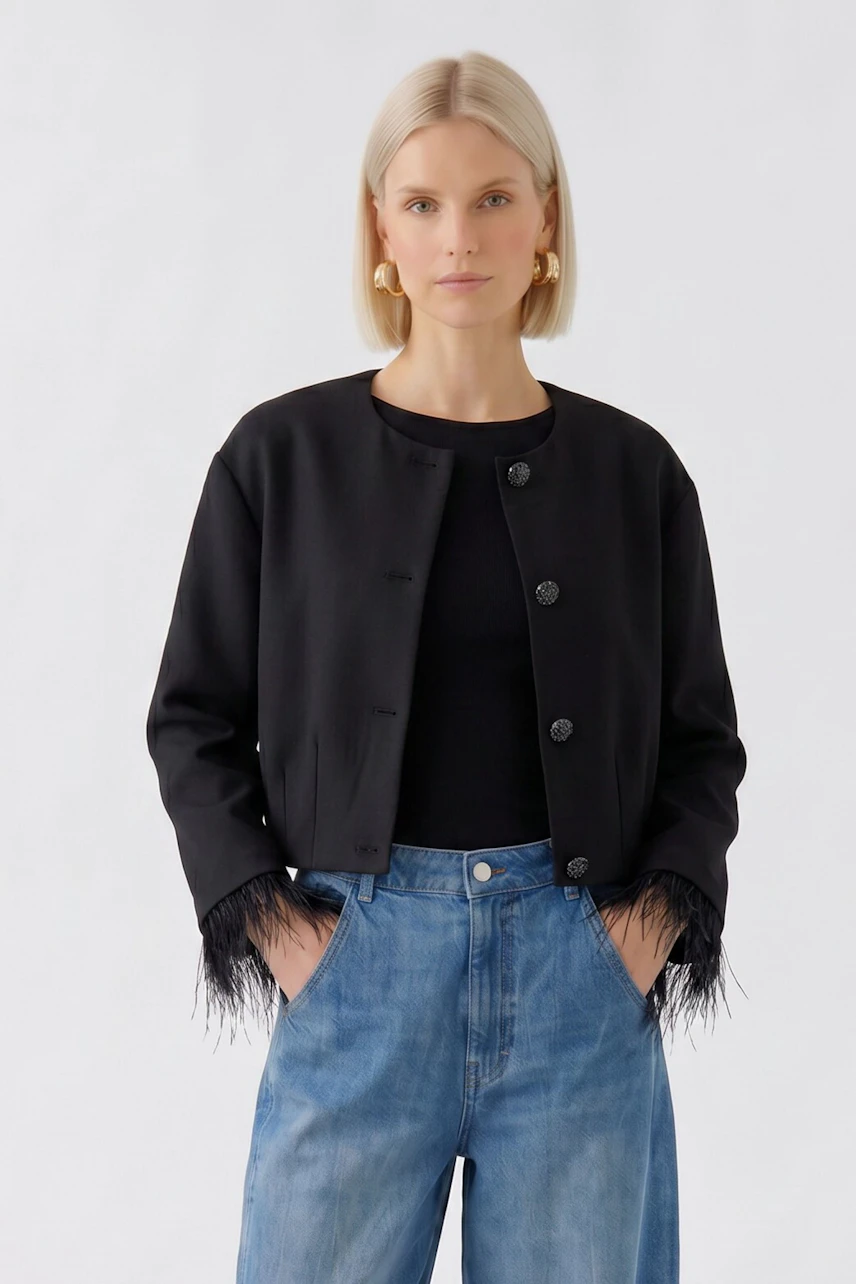Schwarze Damen-Jacke: Frau in schwarzer Jacke mit Fransen und blauer Jeans, lässiger Look.