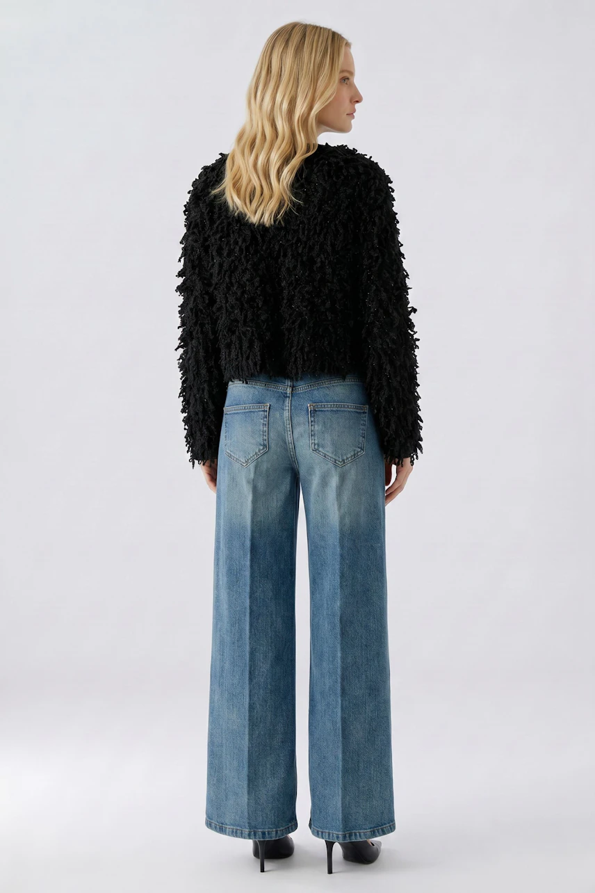 Frau in schwarzer Strickjacke und blauer Jeans, Rückansicht. Lässiger Look für den Alltag.